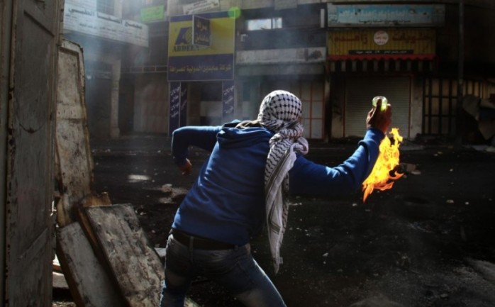 شاب فلسطيني يلقي زجاجة حارقة على قوات الاحتلال