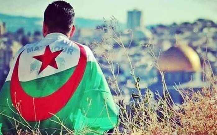 مواطن فلسطيني موشح بالعلم الجزائر ومن أمامه قبة الصخرة المشرفة