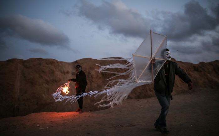 شابان فلسطينيان يحملان طائرة ورقية حارقة على الحدود الشرقية لقطاع غزة.